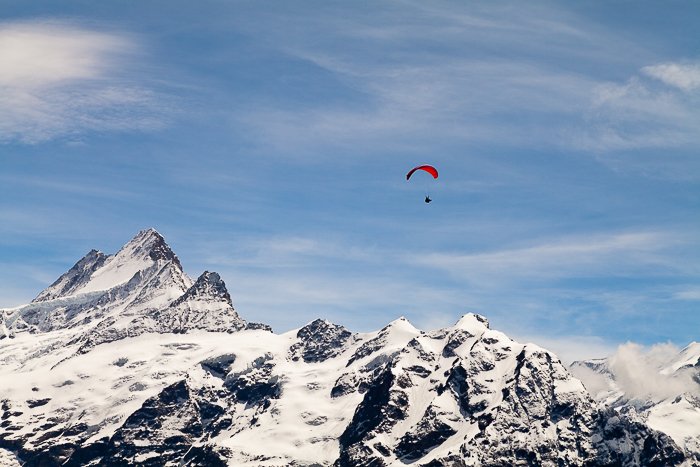 un parapente navegando sobre montañas cubiertas de nieve - habilidades de fotografía de aventura