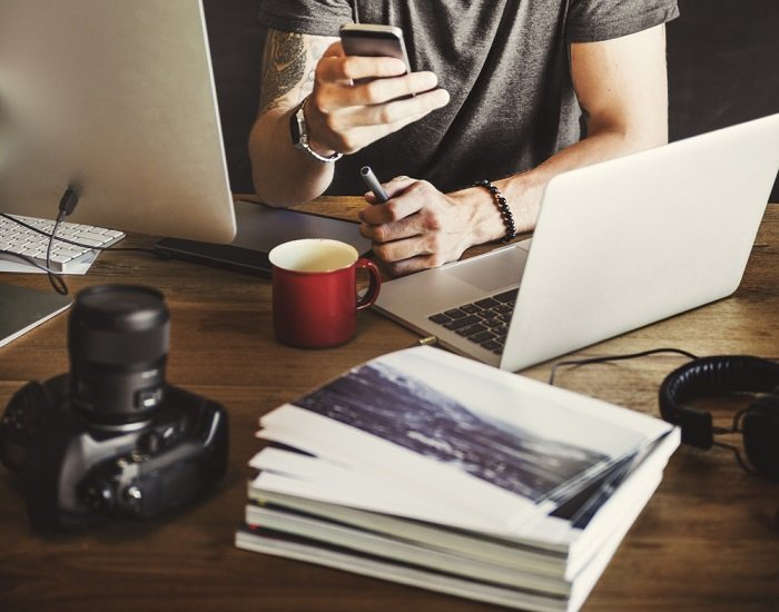 Persona al teléfono frente al escritorio con computadora y cámara