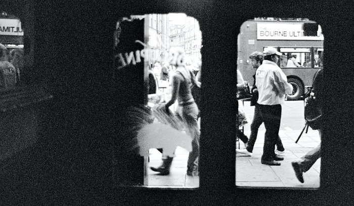 fotografía de una calle muy transitada tomada a través de la vista de las puertas de una tienda de vidrio