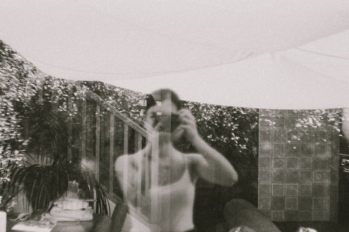 fotografía de películas en blanco y negro de una vista de ventana con el reflejo del fotógrafo también mostrando