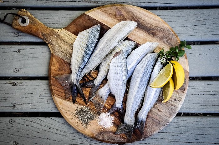 Consejos de fotografía gastronómica: fotografía plana de sardinas preparadas sobre una tabla de madera con guarnición de limón
