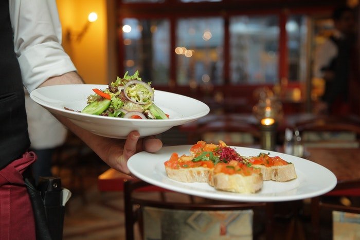 Un camarero con platos de comida deliciosa en un restaurante.