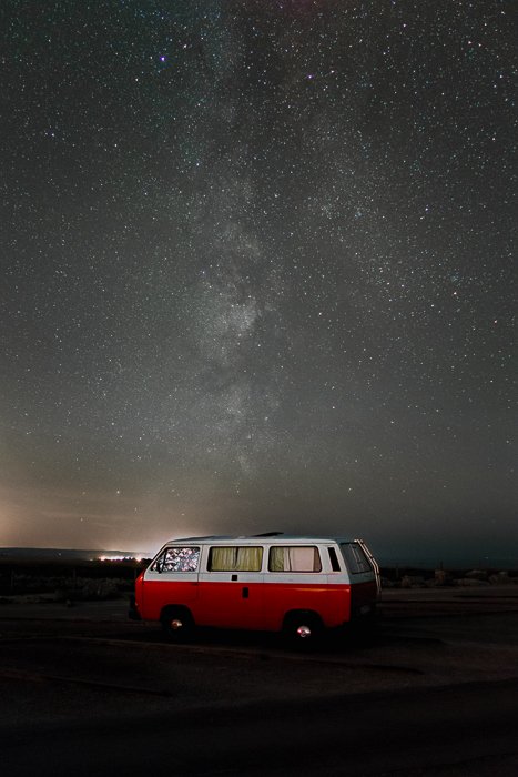 Imagen de una autocaravana roja estacionada bajo un cielo estrellado impresionante después de usar el apilamiento de enfoque para ayudar a eliminar los rastros de estrellas