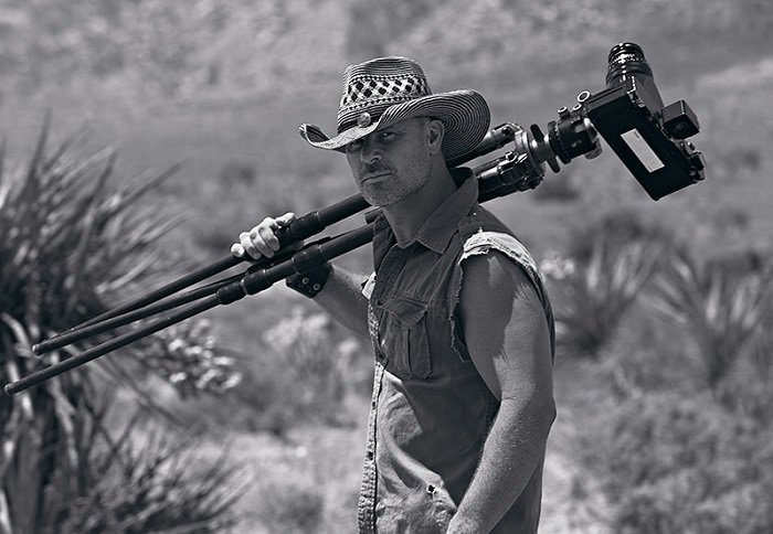 Foto de Peter Lik sosteniendo un trípode en el desierto