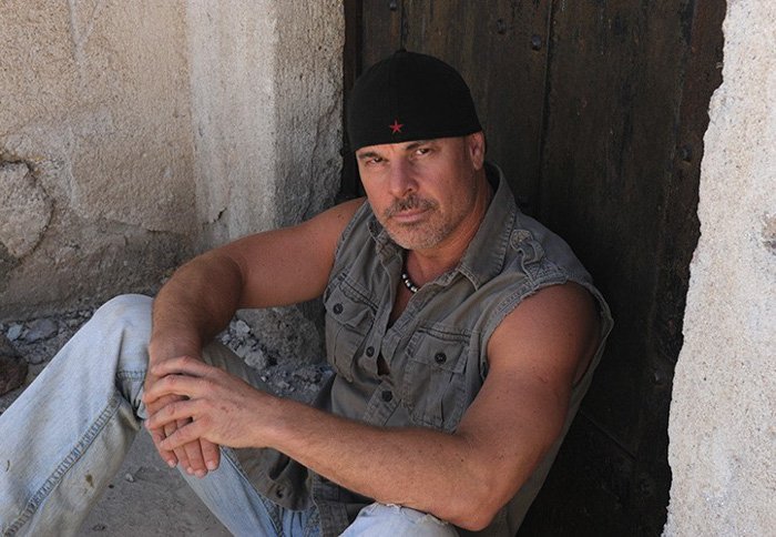 Peter Lik con gorra al revés sentado en la puerta