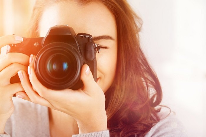 una foto de una mujer apuntando una cámara al fotógrafo que toma la foto