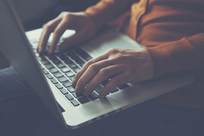 alguien escribiendo en su computadora portátil descansando en su regazo