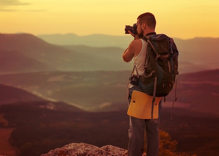 un fotógrafo tomando una foto de una puesta de sol sobre una cordillera