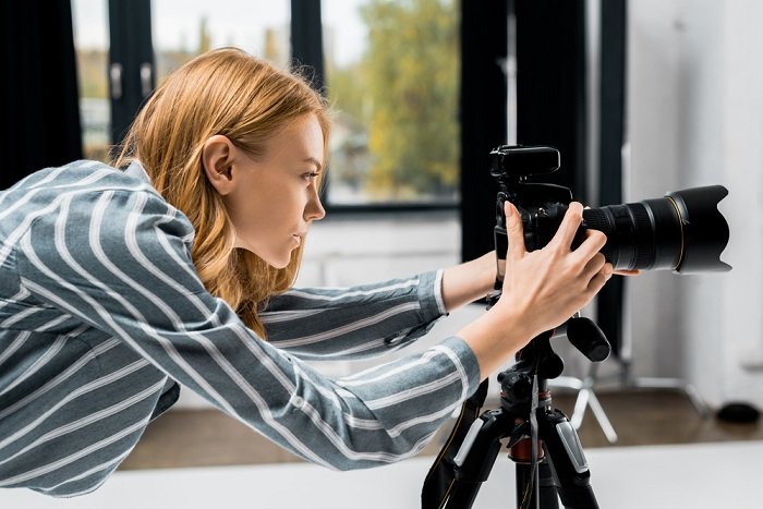 un fotógrafo mirando la configuración de su cámara montada en un trípode