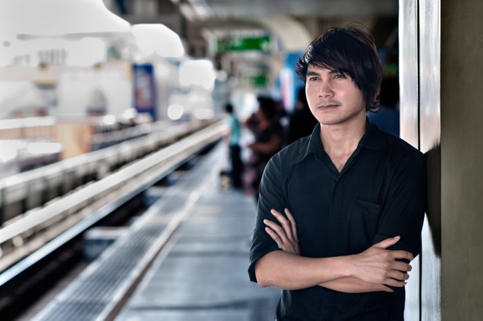 Un modelo masculino posando de pie en una plataforma de tren: consejos de iluminación fotográfica