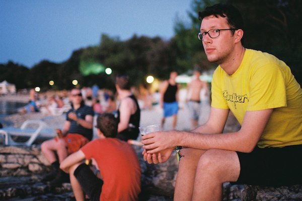 hombre que sienta, en una playa, con, un, cerveza