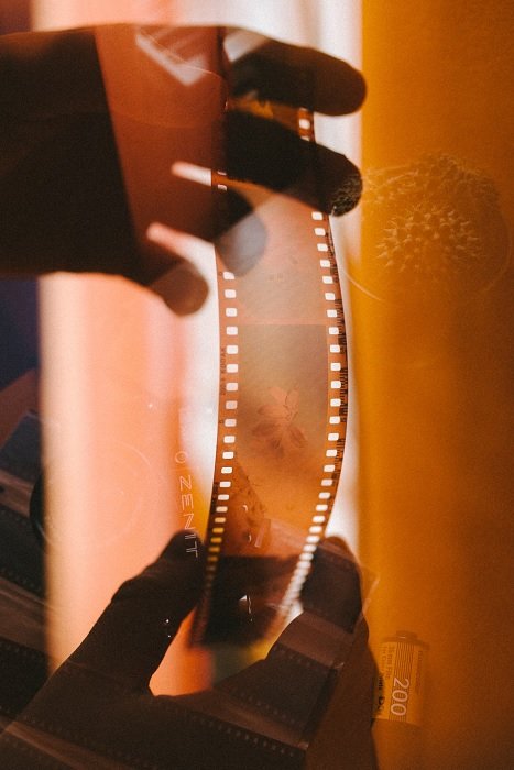 Manos sosteniendo una tira de película negativa para empujar la película