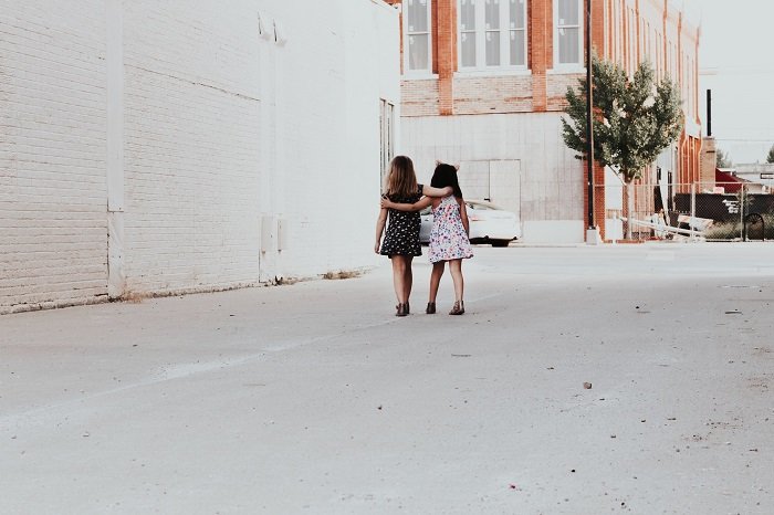 dos niñas caminando del brazo por un callejón como una idea de sesión de fotos hermana