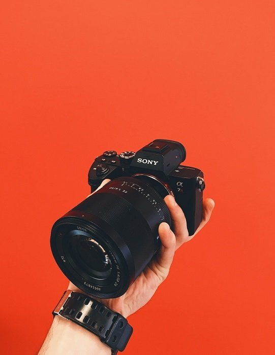 una Sony a7 sostenida en la mano de los fotógrafos con un fondo completamente rojo