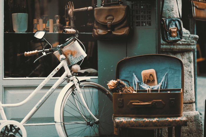 un bodegón al aire libre de antigüedades como una bicicleta, bolsos de cuero y fotos - consejos de fotografía vintage