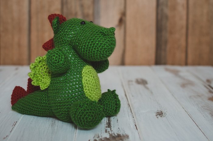 un juguete suave de dinosaurio para niños sobre un fondo de madera de bricolaje