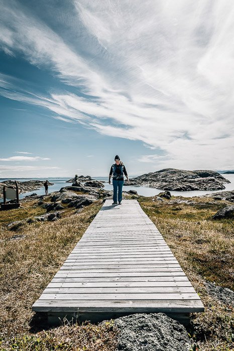 Un fotógrafo al aire libre caminando sobre un puente de madera entre un hermoso paisaje - equipo de fotografía de aventura