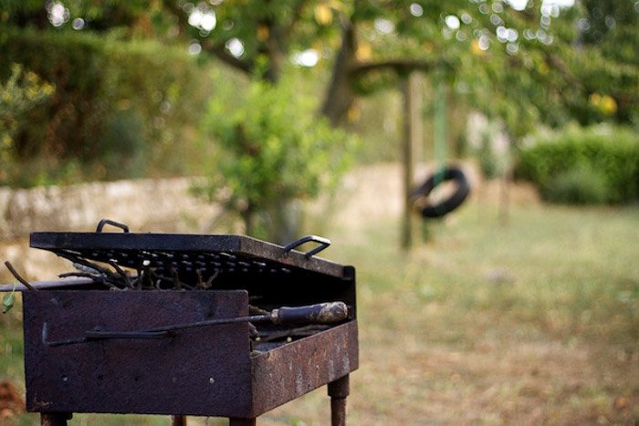 Una vieja barbacoa oxidada y un columpio con una composición desequilibrada