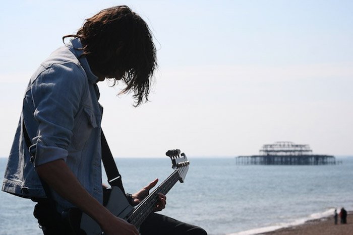 Un hombre tocando la guitarra junto al mar, fotografiado sin centrarse en el equilibrio en la fotografía