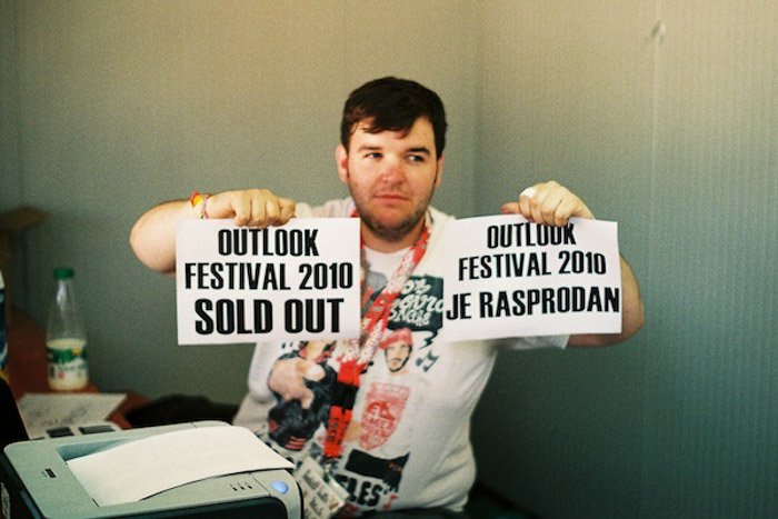 Un hombre sostiene dos carteles impresos que anuncian que las entradas para un festival están agotadas - equilibrio fotográfico