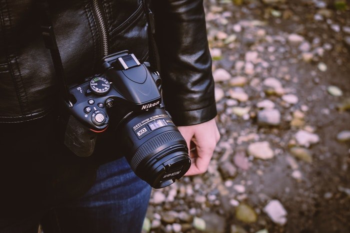 un primer plano de un fotógrafo que lleva una cámara réflex digital Nikon