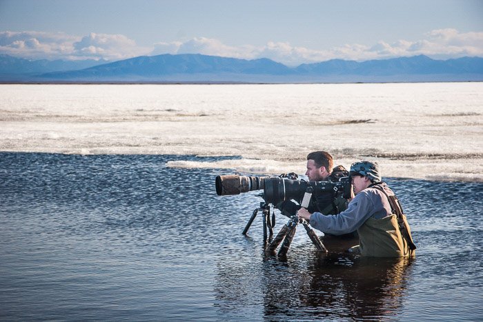 Dos fotógrafos de naturaleza preparándose para fotografiar pájaros en el agua