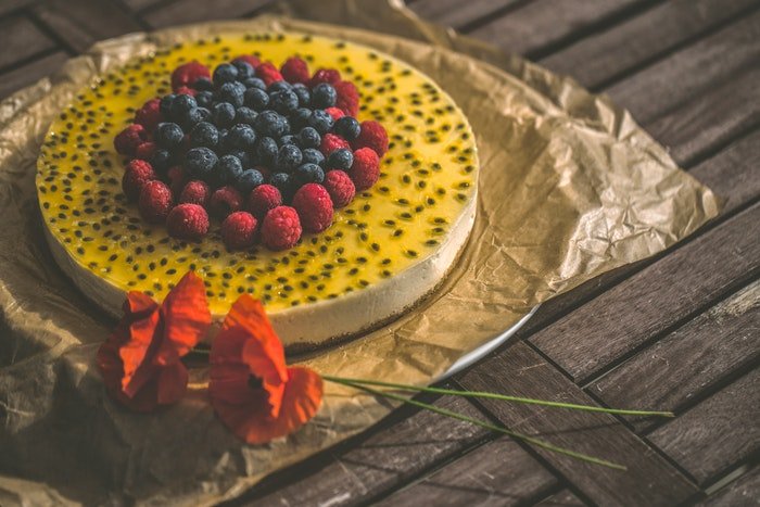 Fotografía de pastel de una tarta de queso con sabor a fruta en una mesa rústica
