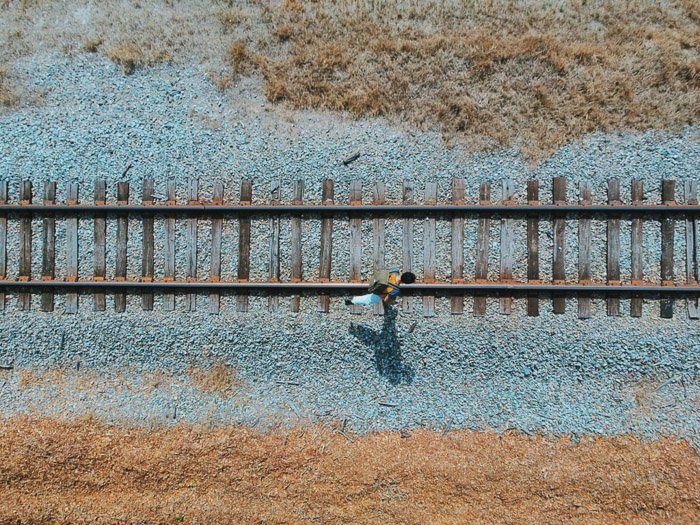 Un ángulo de cámara de vista de pájaro de un hombre caminando a lo largo de las vías del tren