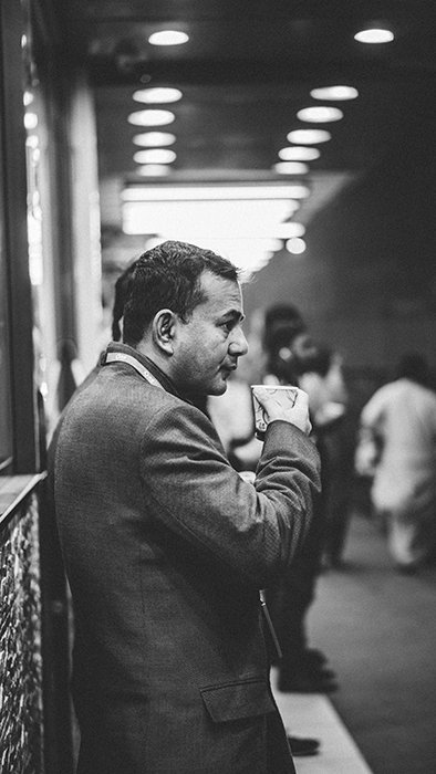 Fotografía callejera en blanco y negro de un hombre tomando café en una estación de tren