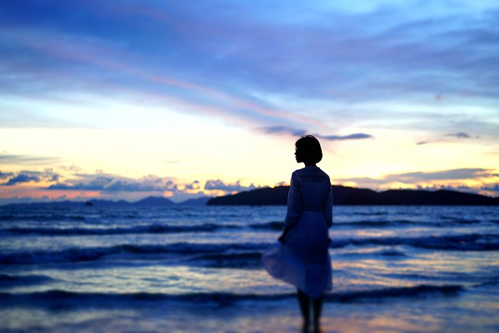 Un ejemplo sincero de fotografía de una mujer en una playa por la noche.
