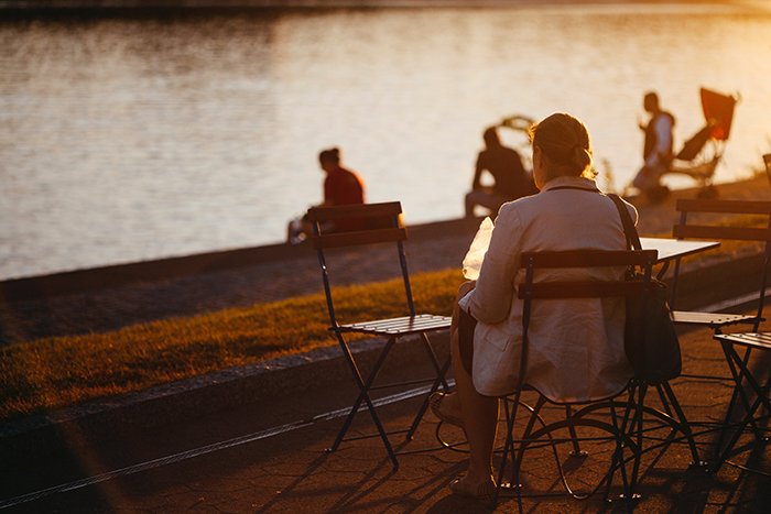 Personas sentadas junto a un río al atardecer