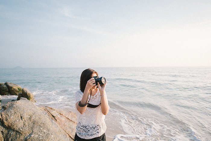 Un ejemplo sincero de fotografía de una mujer tomando fotos en la playa.