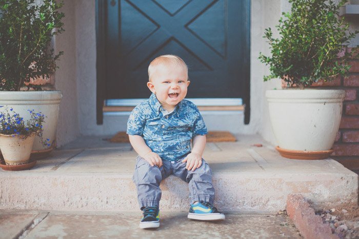 niño feliz sentado en la puerta