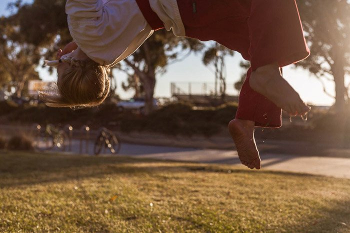 Fotografía infantil sincera de una niña haciendo una voltereta hacia atrás con ropa de artes marciales