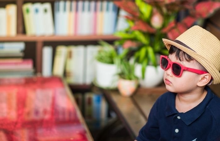 fotografía infantil sincera de un niño pequeño que lleva un sombrero veraniego y gafas de sol