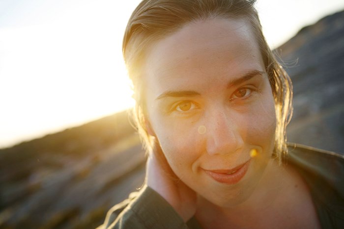 Primer plano retrato de mujer sonriente durante la puesta de sol.