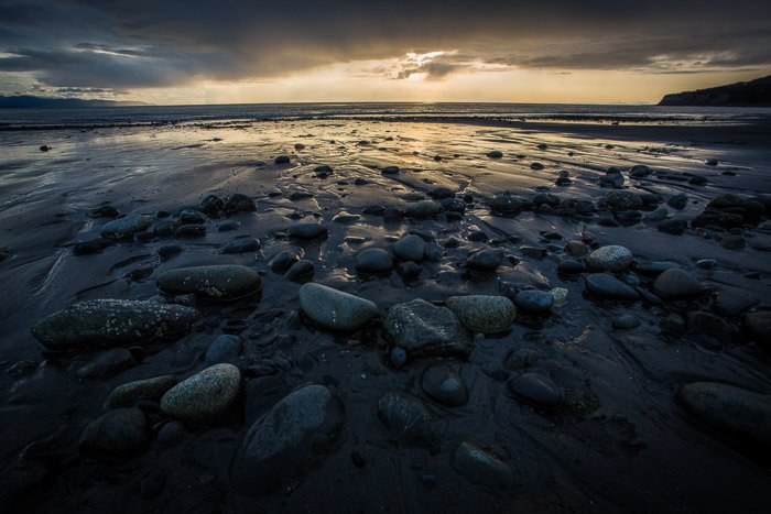 Fotografía costera: rocas de color oscuro en aguas poco profundas al atardecer