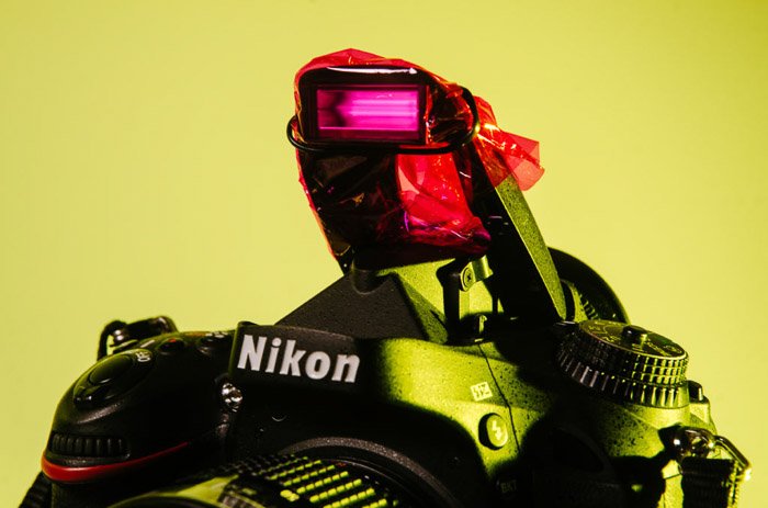 Primer plano de una cámara Nikon con celofán rosa que cubre el flash - fotografía de gel de color