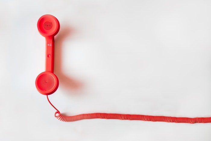 Teléfono rojo sobre un fondo blanco.