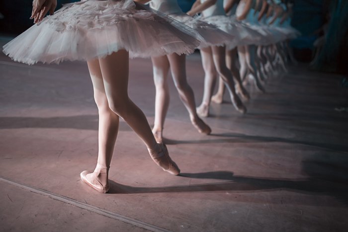 Las piernas de una fila de bailarines en tutú blanco sincronizaron el baile en el escenario