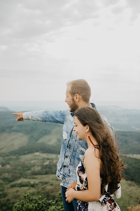 Retrato de una pareja posando naturalmente en la cima de una colina