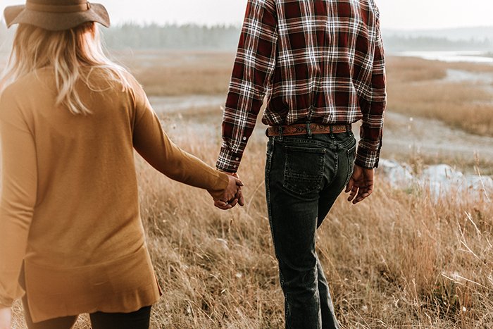 Una pareja cogidos de la mano y paseando por el campo.