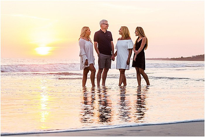 Un dulce retrato de una familia de cuatro personas posando en la playa al atardecer - fotografía emocional