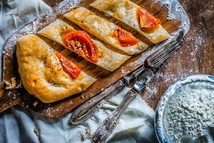 pan plano con tomates en una bandeja de madera