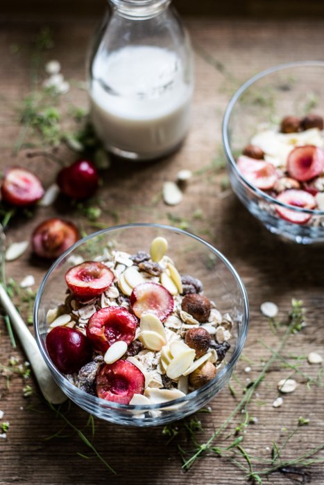fruta y avena en un bol, cerca de una botella de leche en una mesa de madera