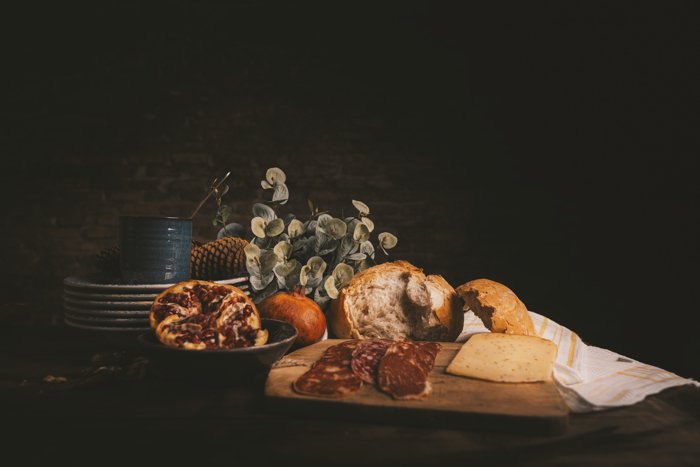 Foto de naturaleza muerta con brad, jamón, queso y platos sobre una mesa