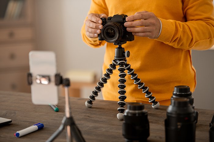 Manos de fotógrafo profesional fijando photocamera en trípode en la mesa.