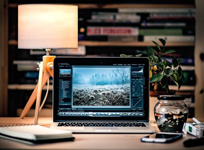 Una computadora portátil, una computadora portátil, un teléfono y otros artículos en la mesa de una oficina de fotógrafos profesionales