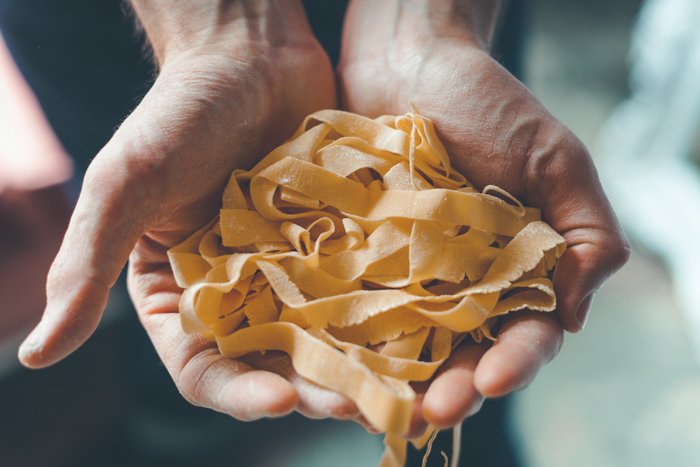 Fotografía de comida de manos sosteniendo pasta fresca.