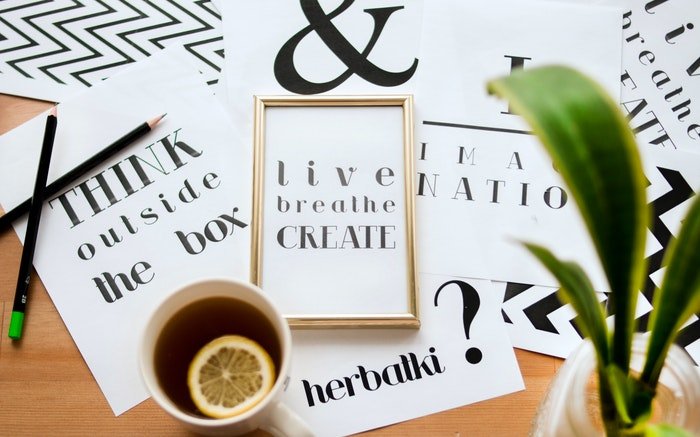Plano de diferentes tipografías, una taza de té, una planta y papelería.